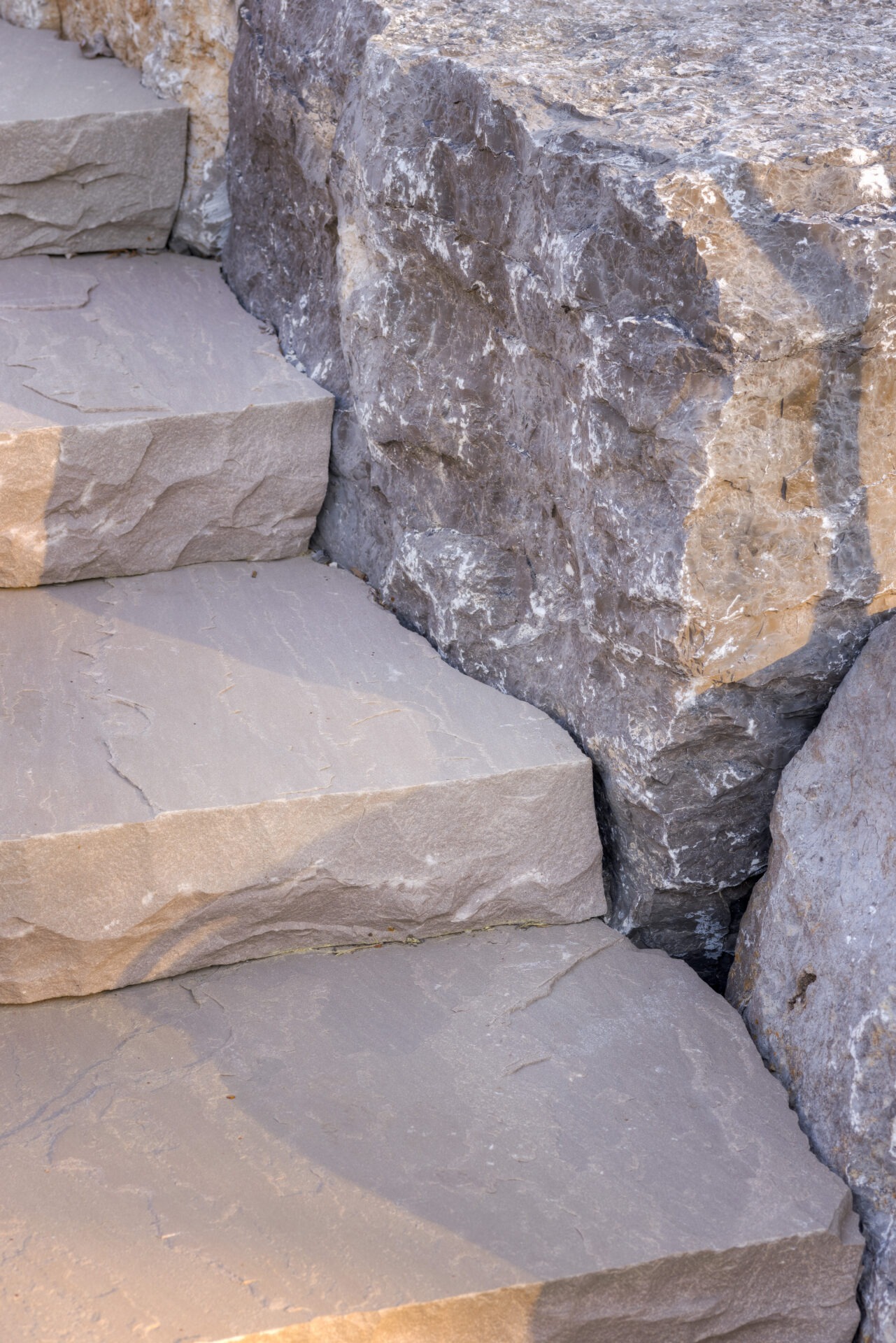 This image depicts a close-up view of stone steps, showcasing varying shades of gray and textures, with natural sunlight casting shadows on the surfaces.