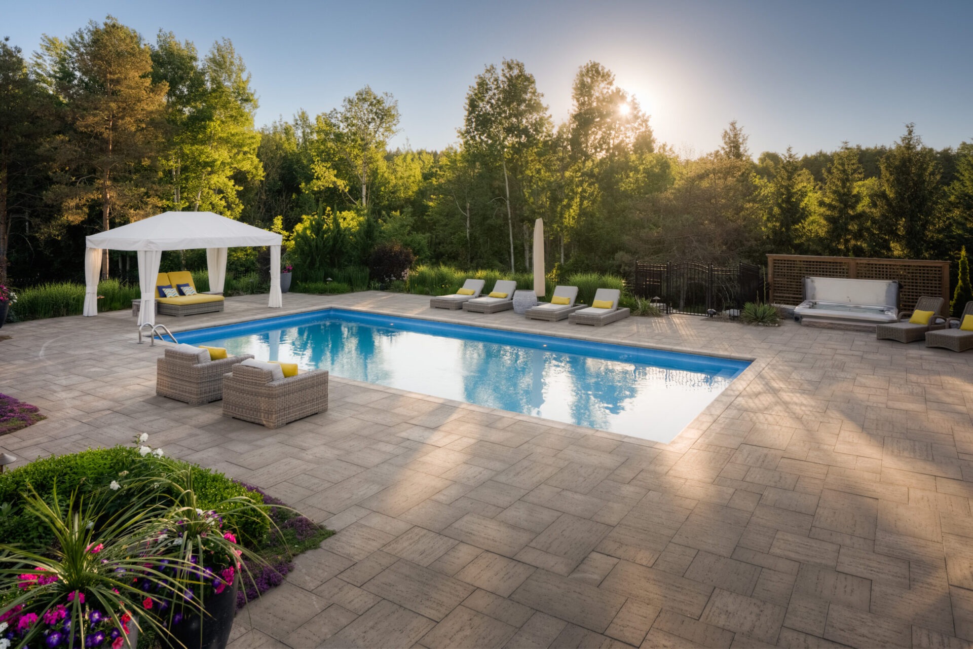 The image features a tranquil backyard with a rectangular swimming pool, loungers, an elegant gazebo, hot tub, and a patio, surrounded by lush greenery at sunset.